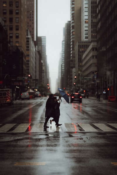 人黑夹克拿着伞走在行人巷白天
